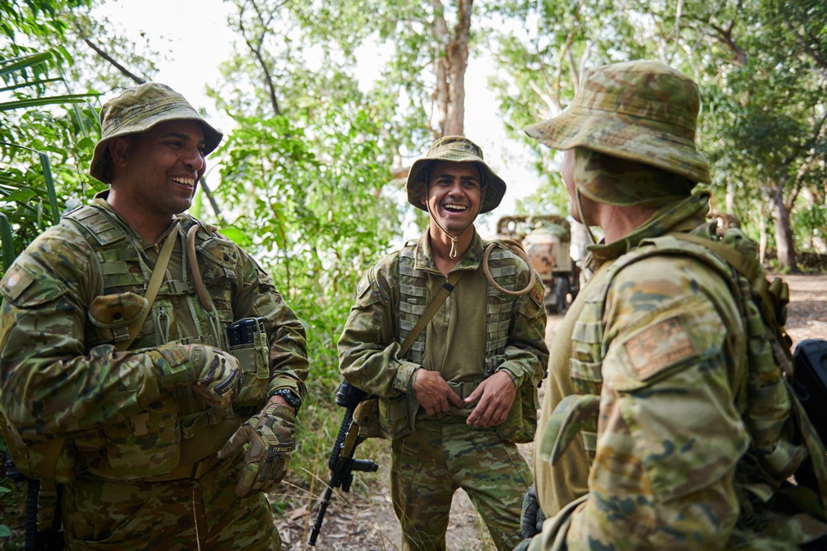 Three indigenous Navy sailors smile to camera in a tropical environment