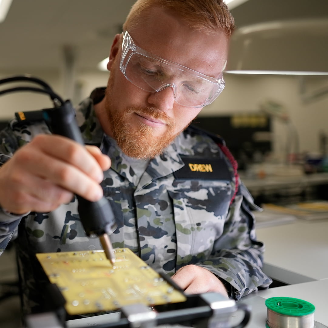 Electronics Technician Bronson works on a motherboard.