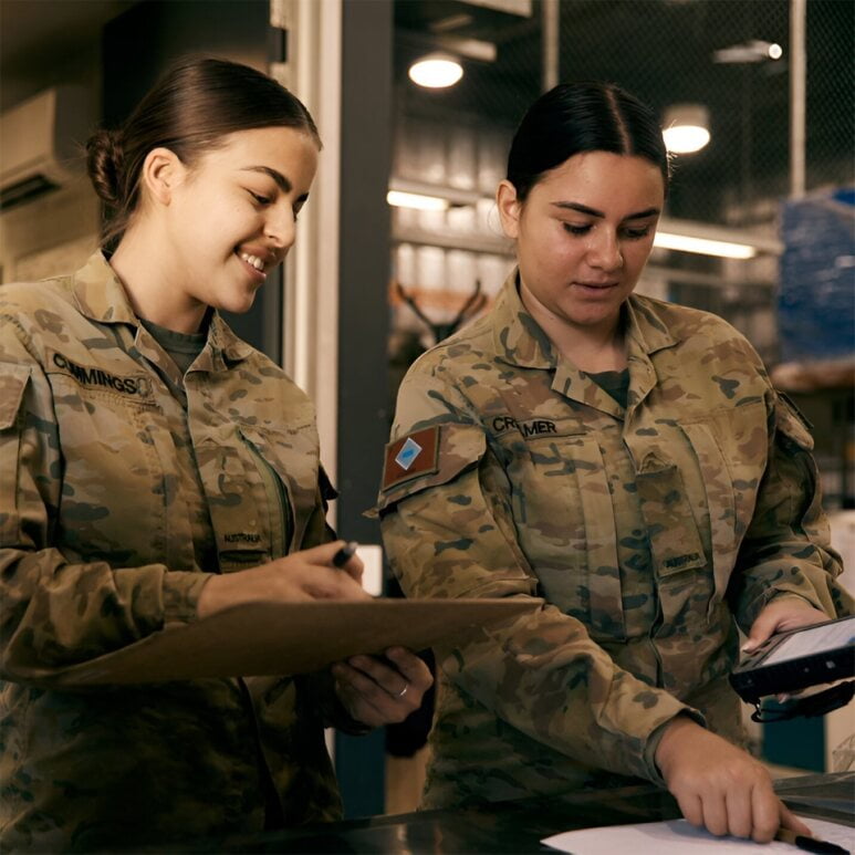 Two women in Army uniform work together.
