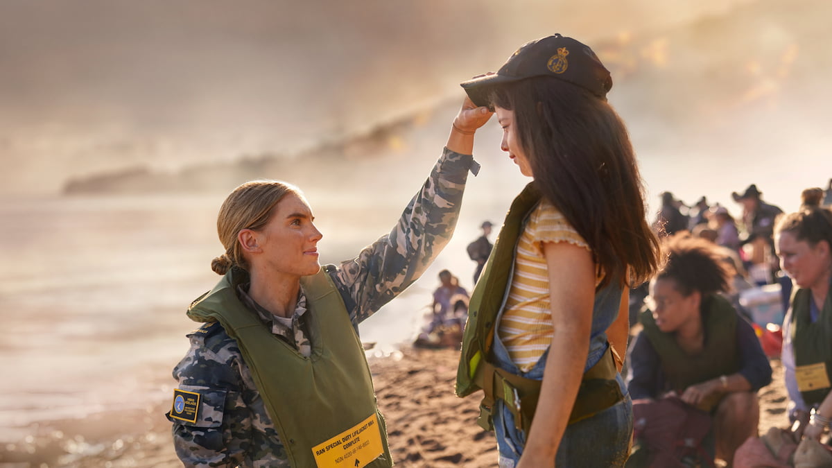 A member of the Navy outside on a beach with a young girl.