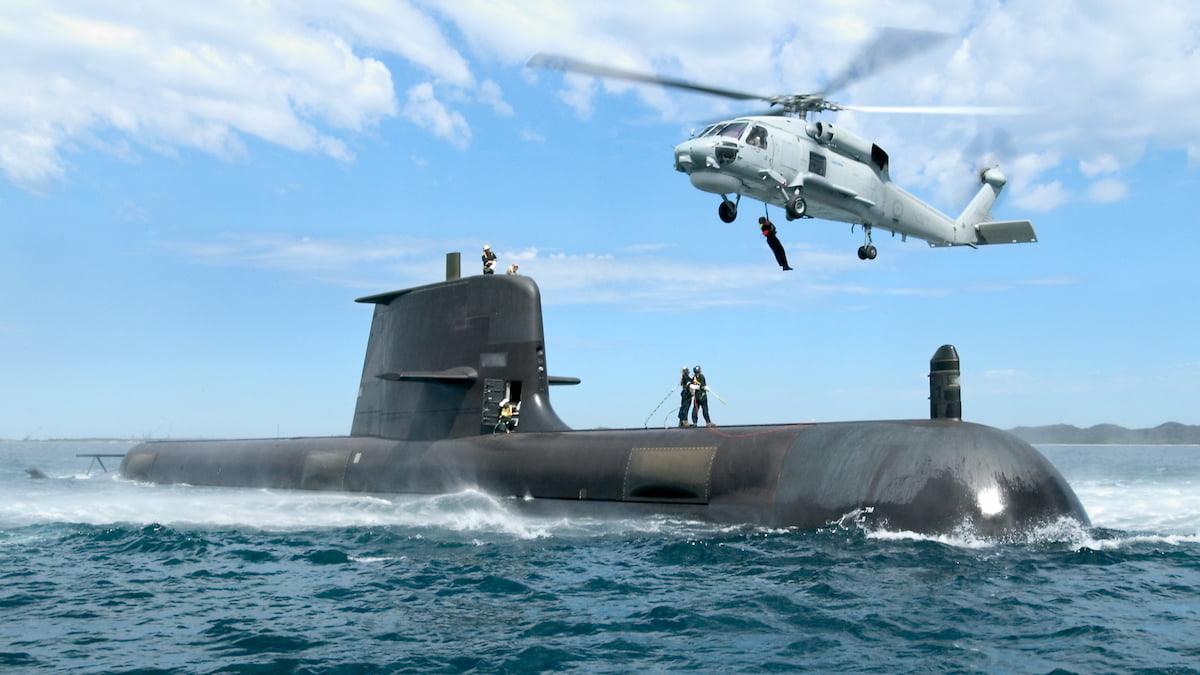 A helicopter flying over a submarine.