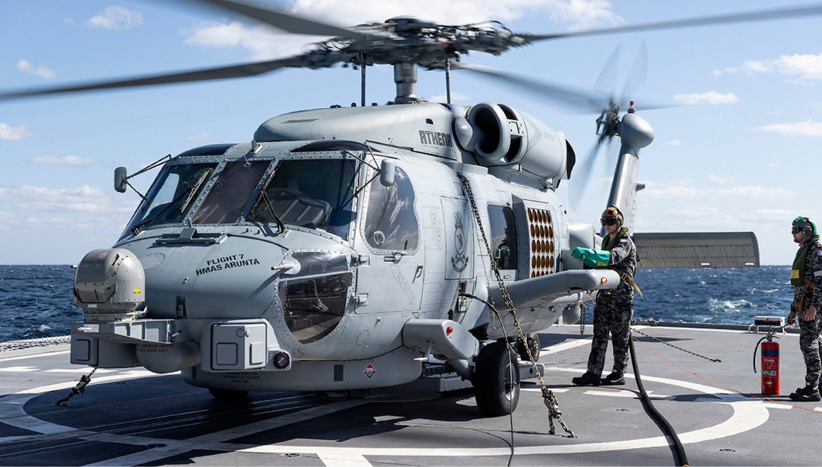 A chopper lands on a Navy ship at sea.