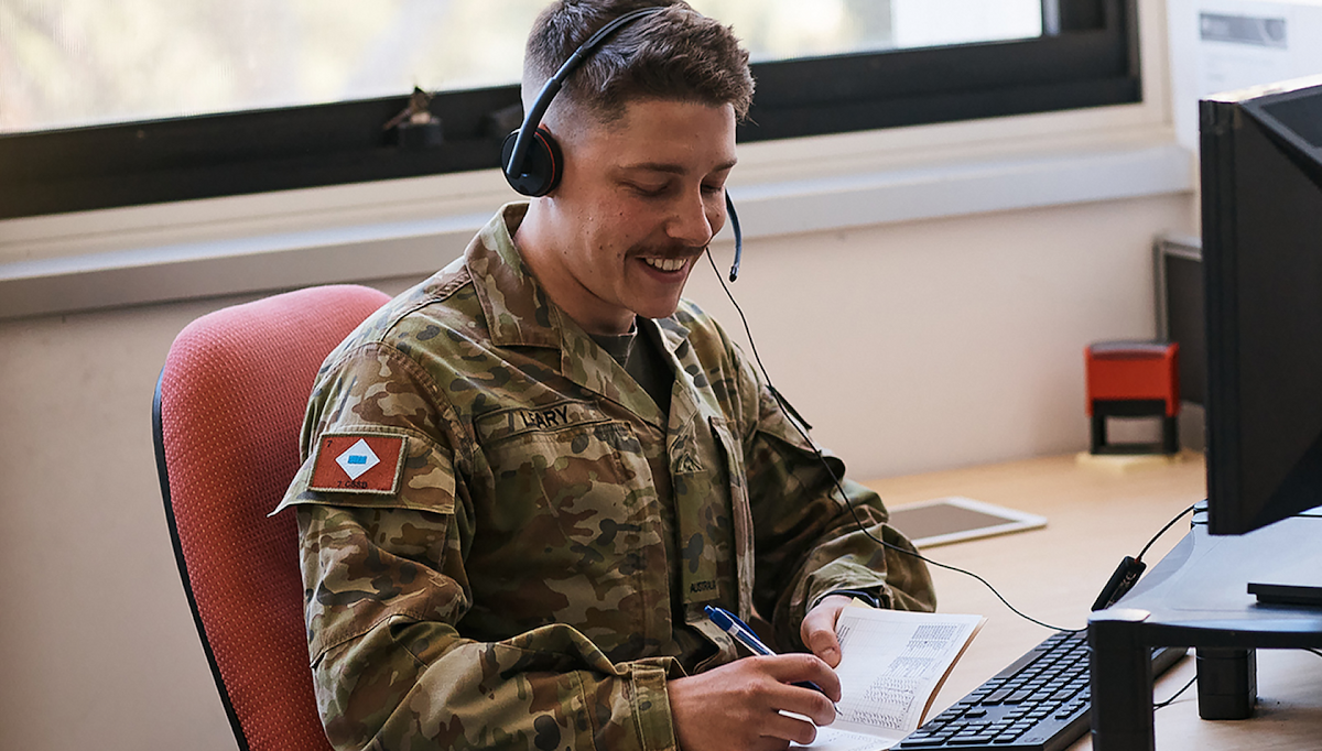 A member of the Navy wears a headset for communication at his desk.