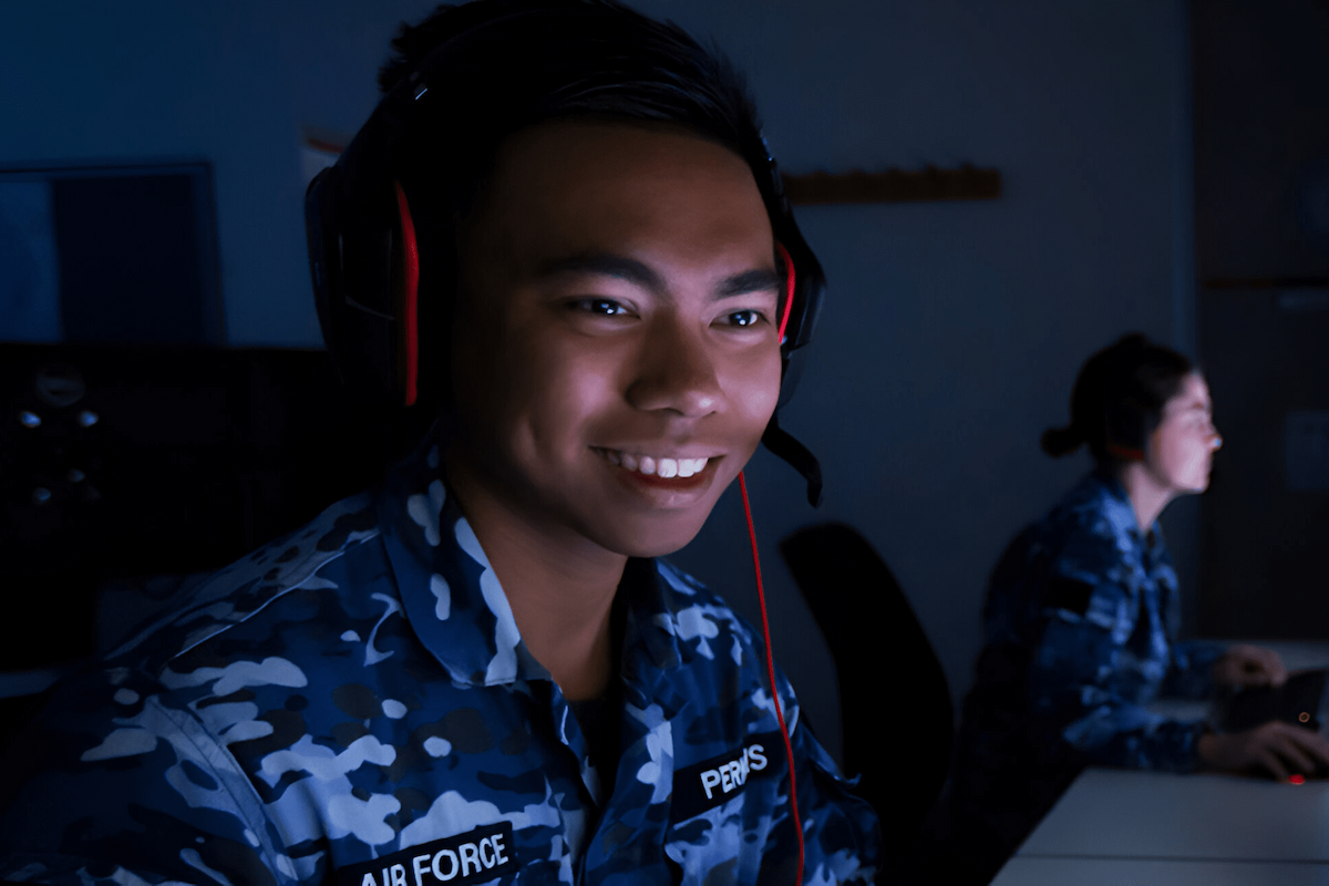 A member of the Air Force sits in a dark room wearing headphones.