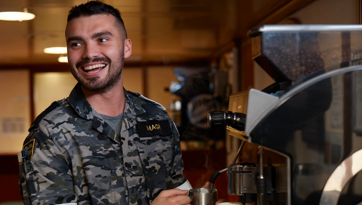 A man in Navy uniform smiles to himself.