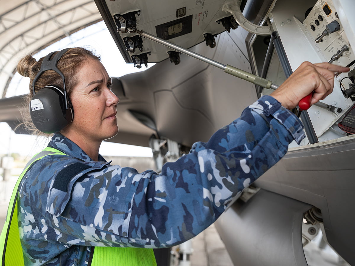 A woman in the Air Force  works on an aircraft.
