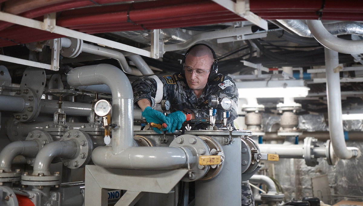 A member of the Navy works in the engine room.