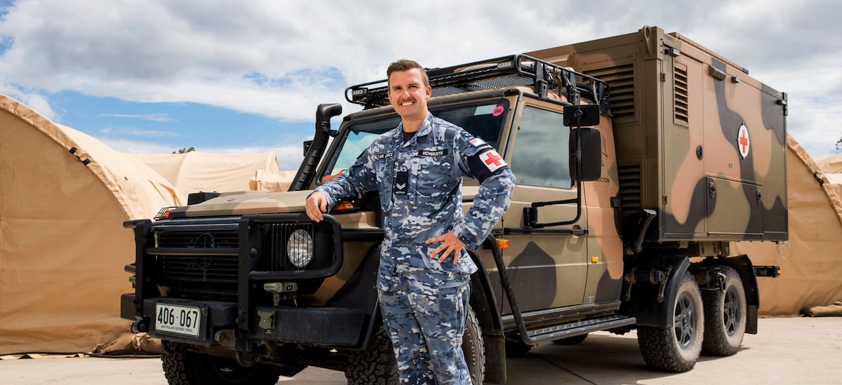 A member of the Air Force leaning against a truck smiling.