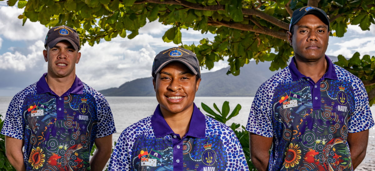 Three indigenous Navy Sailors in a tropical environment share a laugh. 