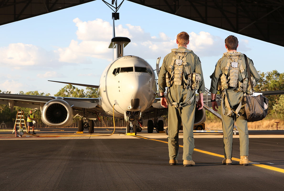Two members of the Air Force standing outside looking at an airplane.