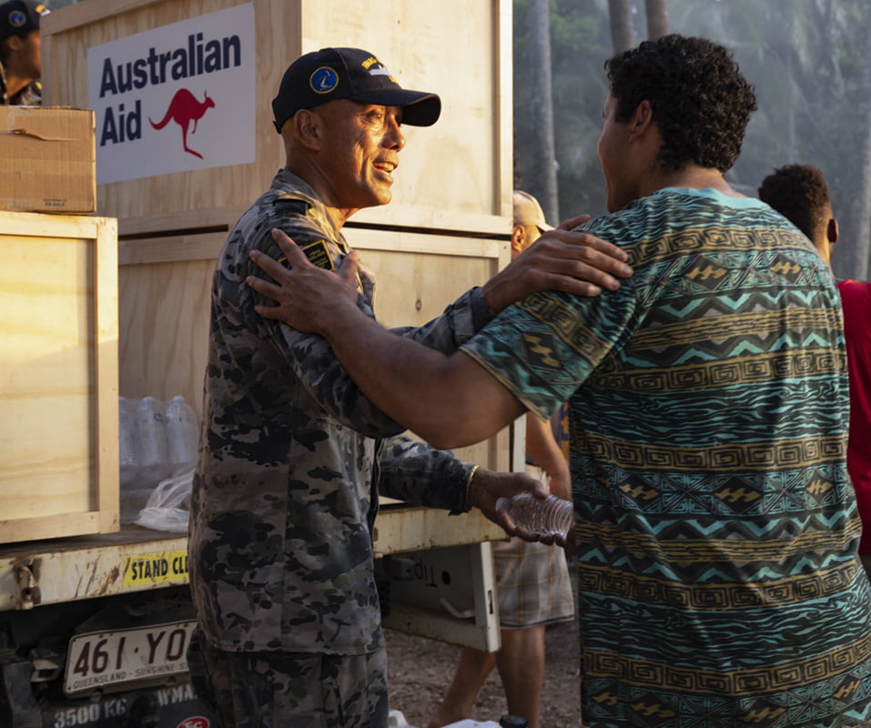 A member of the Navy distributes water to a man in need.