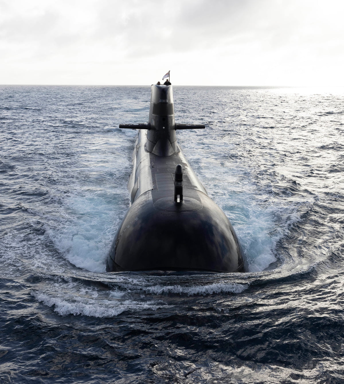A submarine glides through the water on a sunny day, showcasing its sleek design and underwater capabilities.