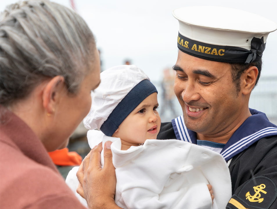 A memeber of the Navy looking happily at his small child.