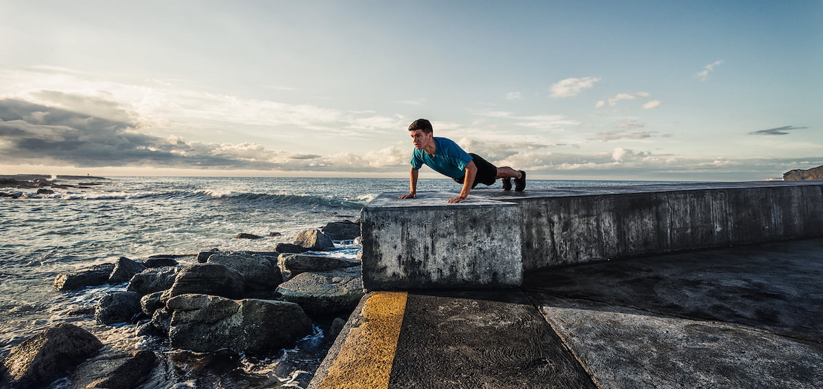 A man completes a push up by the ocean.