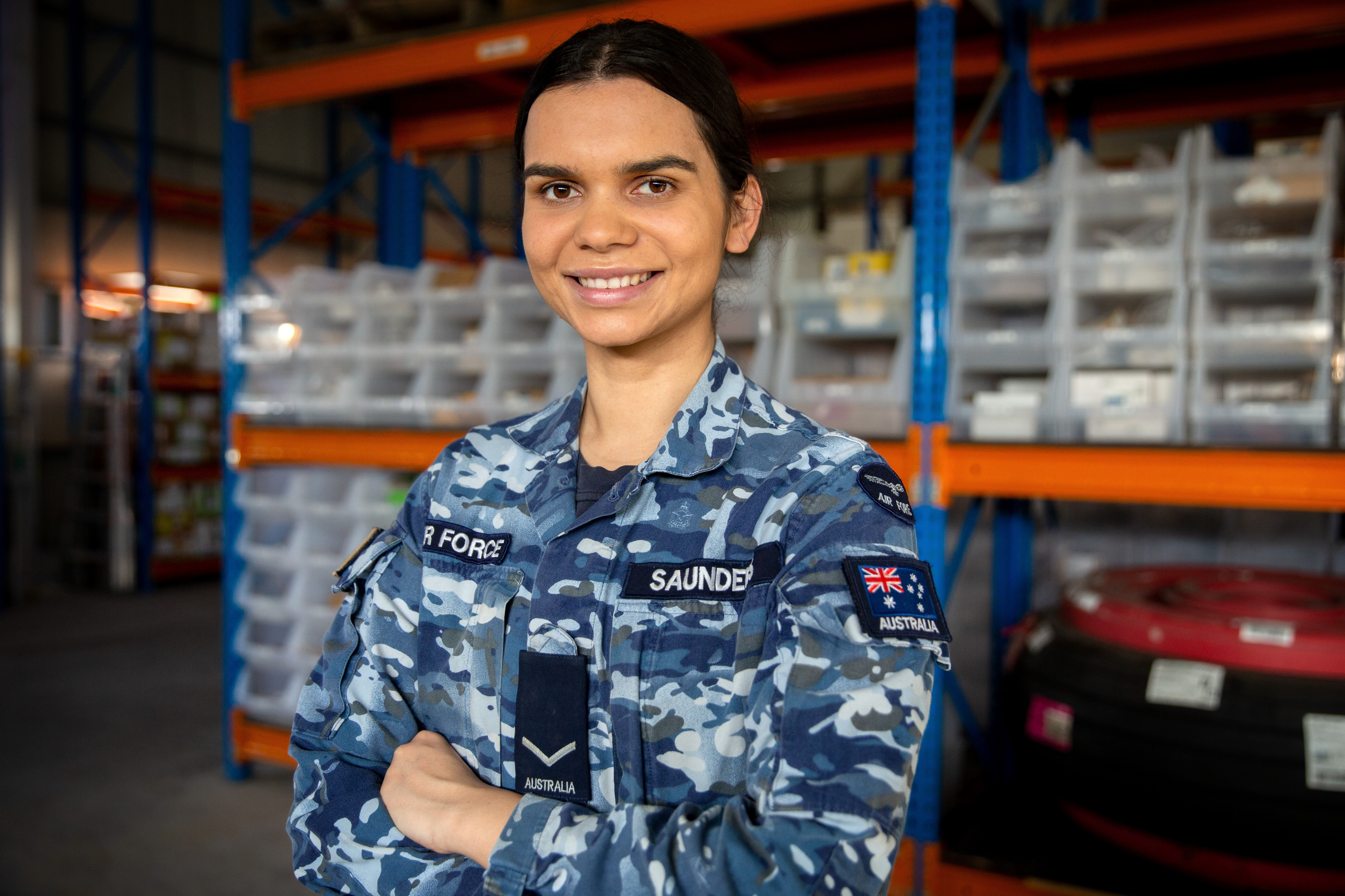 An Air Force member in uniform smiling with her arms crossed.